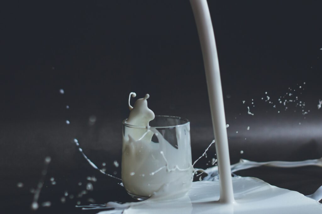 Glass of milk with milk spilled over table